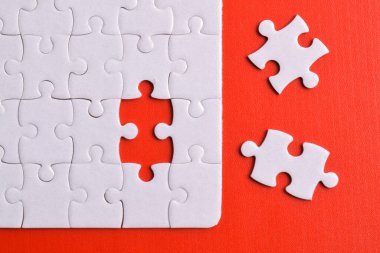 Kırmızı arka planda kayıp parçalı beyaz bulmaca. Düz yatıyordu. Üst görünüm