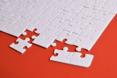 Kırmızı arkaplanda eksik parçalı beyaz bulmaca.