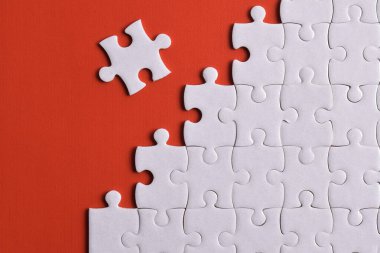 Kırmızı arka planda beyaz yapboz parçaları. Düz yatıyordu. Üst görünüm