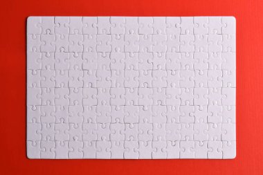 Kırmızı arka planda beyaz yapboz parçaları. Düz yatıyordu. Üst görünüm