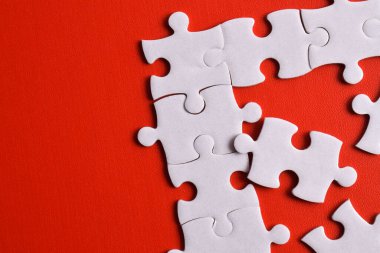 Kırmızı arka planda beyaz yapboz parçaları. Düz yatıyordu. Üst görünüm