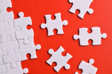 Kırmızı arka planda beyaz yapboz parçaları. Düz yatıyordu. Üst görünüm