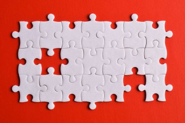 Kırmızı arka planda beyaz yapboz parçaları. Düz yatıyordu. Üst görünüm