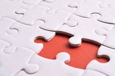 Kırmızı arkaplanda eksik parçalı beyaz bulmaca, yakın plan