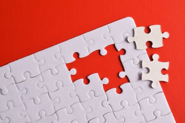 Kırmızı arka planda kayıp parçalı beyaz bulmaca. Düz yatıyordu. Üst görünüm