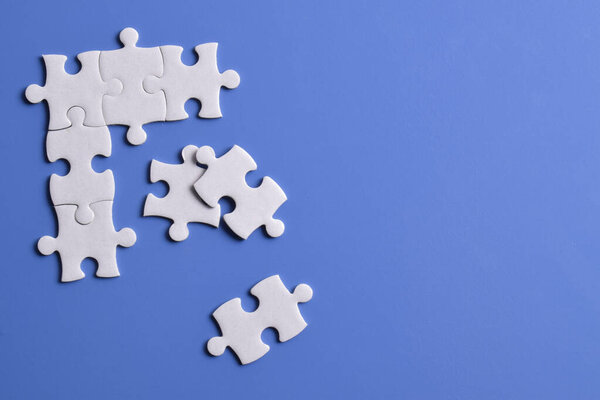 White puzzle pieces on blue background. Copy space for text, top view.