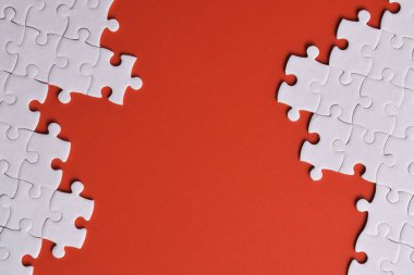 Kırmızı arka planda beyaz yapboz parçaları, üst manzara. Metin için boşluk