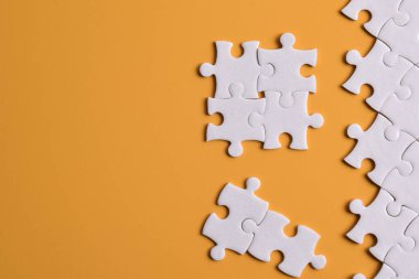 Turuncu arka planda beyaz yapboz parçaları, üst manzara. Metin için boşluk