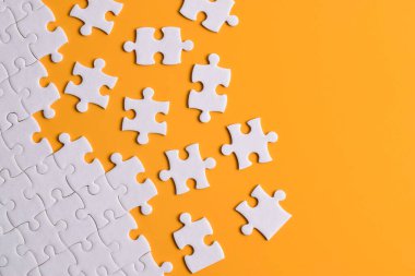 Turuncu arka planda beyaz yapboz parçaları. Düz yatıyordu. Üst görünüm