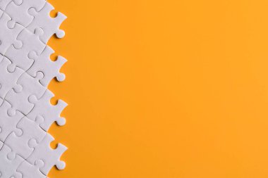 Turuncu arka planda beyaz yapboz parçaları, üst manzara. Metin için boşluk