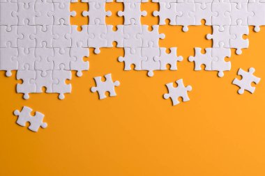 Turuncu arka planda beyaz yapboz parçaları. Düz yatıyordu. Üst görünüm