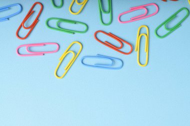 Açık mavi arkaplanda izole edilmiş renkli ataçlar. Uzayı kopyala Metnin ve bilgilerin için alanı kopyala