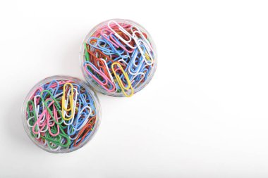 Beyaz arkaplanda renkli ataçlarla dolu bir kavanozun üst görünümü