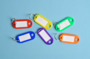 Açık mavi arkaplanda izole edilmiş renkli plastik anahtar etiketi