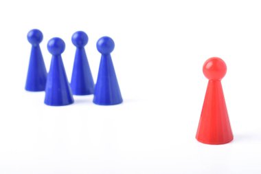 Kırmızı oyun parçası beyaz arka plandaki mavi parçalardan ayrı duruyor, liderliği, bireyselliği, farklılığı, takım çalışmasını veya sosyal konseptleri sembolize ediyor..