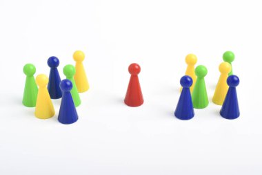 Beyaz arka planda iki renkli piyon grubu ile karşılaşan kırmızı oyun parçası, liderliği, pazarlığı, arabuluculuğu ya da karşı taraflar arasında karar vermeyi sembolize ediyor.