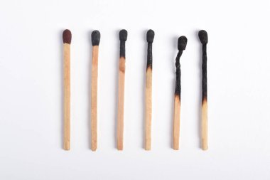 Beyaz arkaplanda yanmış eşleşmeler var. Yanan kibritlerin farklı aşamaları.