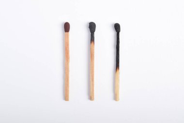 Beyaz arkaplanda yanmış eşleşmeler var. Yanan kibritlerin farklı aşamaları.