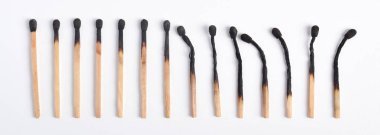 Beyaz arkaplanda yanmış eşleşmeler var. Yanan kibritlerin farklı aşamaları.