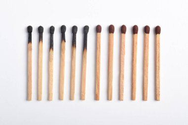 Beyaz arkaplanda yanmış eşleşmeler var. Yanan kibritlerin farklı aşamaları.