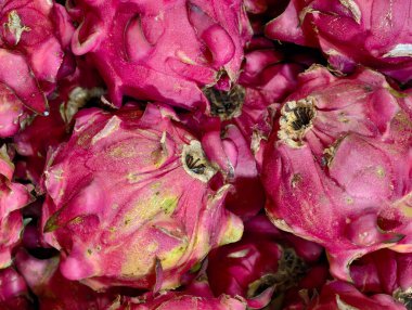 A close-up view of a pile of fresh, vibrant pink dragon fruits.
