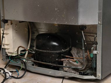 Buzdolabının iç çalışmalarının yakın görüntüsü, kompresör ve soğutma sistemine odaklanıyor.