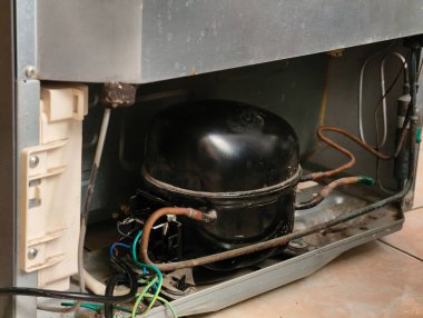 Buzdolabının detaylı görünümü sıkıştırıcı ünitesi ve elektrik bağlantıları, iç bileşenleri gösterir.