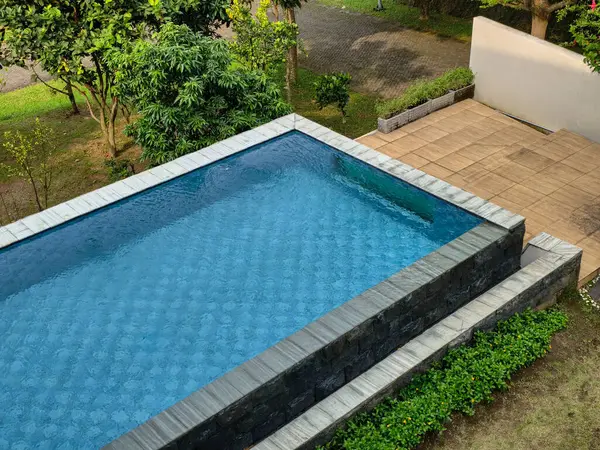 Berrak mavi sularla çevrili sakin ve davetkar bir yüzme havuzu. Taş ve yemyeşil bitkilerle çevrili. Huzurlu bir kaçış öneriyor..