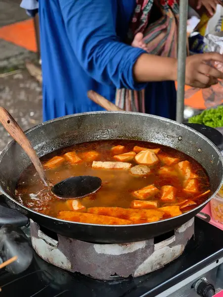 Lezzetli et suyu ve malzemelerle dolu büyük bir tavanın yakından çekimi, bir sokak yemeği satıcısı tarafından hazırlanıyor..