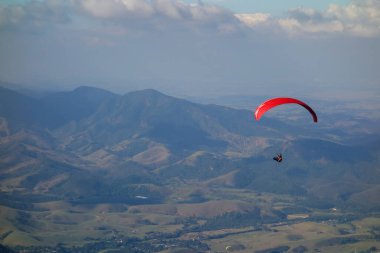 Güneşli bir günde dağ vadisinde uçan kırmızı Paraglider.
