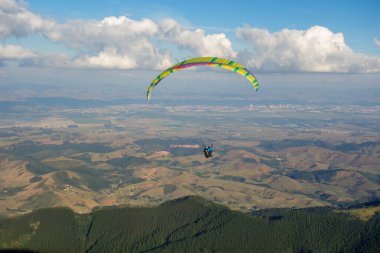Güneşli bir günde dağ vadisinde uçan renkli Paraglider.