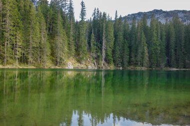 Durmitor Ulusal Parkı, Zabljak, Karadağ 'daki Zminje gölünün yeşil yüzeyi gün batımını yansıtıyor.