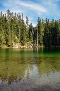 Durmitor Ulusal Parkı, Zabljak, Karadağ 'daki Zminje gölünün yeşil yüzeyi gün batımını yansıtıyor.