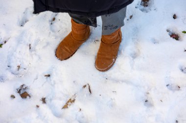 Woman's boots on the snow beside footprints