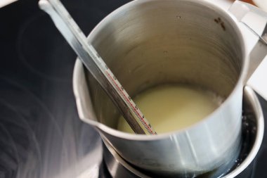 Heat measuring jug of water and jojoba oil in boiling water, record the temperature with a thermometer