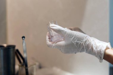 Gloved hands holding the cosmetic empty bottle in the laboratory