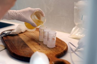 Pouring jojoba oil into the empty cosmetic bottles
