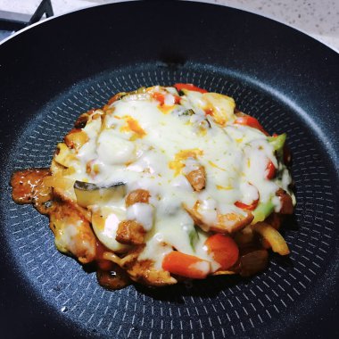 Making a mini tortilla mozzarella combination pizza in the pan