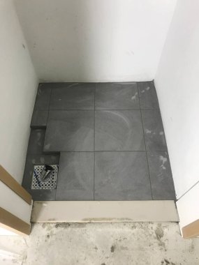 The floor tiles and drain of laundry room