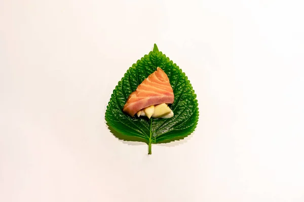 Sliced salmon and garlic on the fresh sesame leaf, arranged perilla leaf