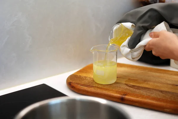 Pouring the jojoba oil into the beaker of water in the laboratory