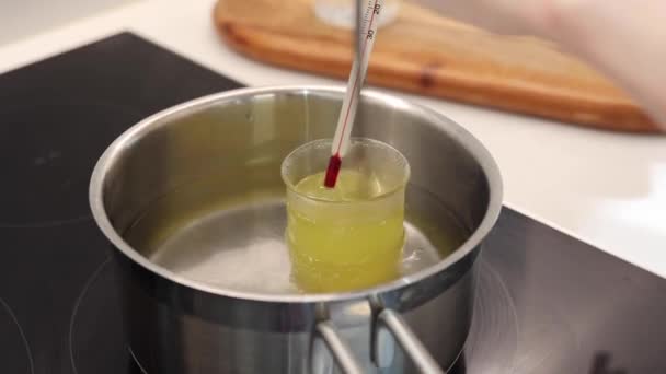 熱湯の中の水とホホバ油の熱ビーカー 温度計で温度を記録します — ストック動画
