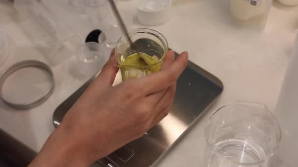 ビールに油と蜜蝋をスプーンで混ぜ 実験室内の電子スケールで成分を計量します — ストック動画