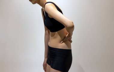 Woman puts her hand on ribs in black sportswear