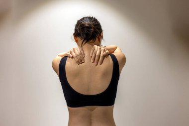 Woman puts her hands on shoulders in black sportswear