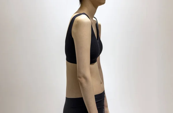 Side view of woman\'s round shoulders in black sportswear