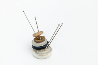 Yatay fotoğraf, beyaz arkaplanda iğne dolu düğmeler, kopyalama uzayı. Hobileri ve el sanatları kavramını.