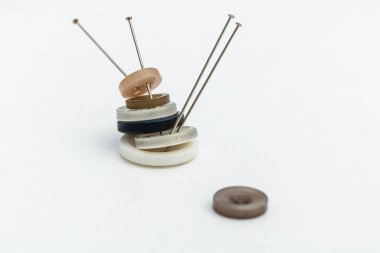 Yatay fotoğraf, beyaz arkaplanda iğne dolu düğmeler, kopyalama uzayı. Hobileri ve el sanatları kavramını.