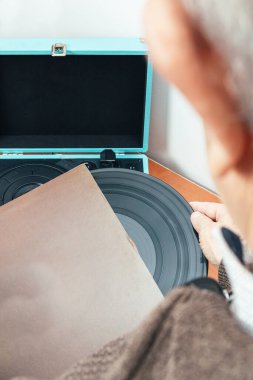 Dikey fotoğraf, Kafkas yetişkin erkek, geri döndü, kahverengi kolundan bir vinil alarak, mavi bir evrak çantası şeklinde bir pikaba koydu. Kavram hobileri, sanat.