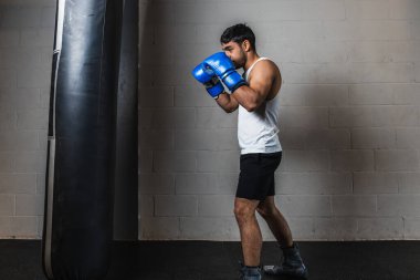 Yatay fotoğrafçı genç yetişkin karışık ırk eğitimi almış kum torbası ve mavi eldivenli, spor salonunda. Uzayı kopyala Spor, eğlence konsepti.